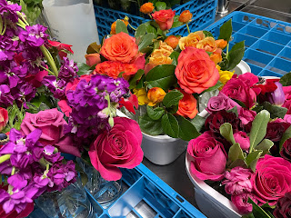 purple, orange, and pink roses and flowers in plastic tubs