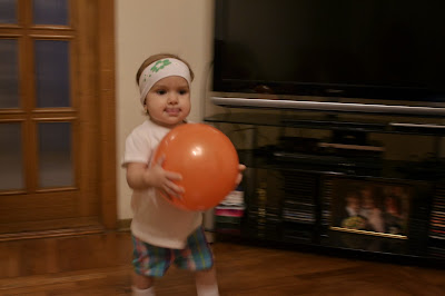 a small girl is holding an orange ball in the living room, playing