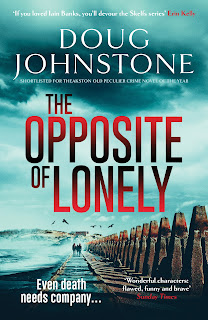 Cover for book "The Opposite of Lonely" by Dough Johnstone. Against a background of clashing seas, a row of "dragons' teeth" anti-tank defence - tapered concrete posts - stretched away into the distance, running alongside the right had side of a causeway leading to an island with concrete structures visible on it. Three figures in silhouette are just visible walking away along the causeway towards the island.