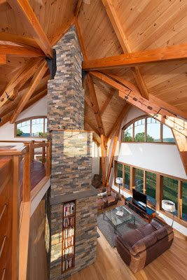 The home design features a central hearth and chimney supporting a timber frame which mimics a canopy of trees in a grove.