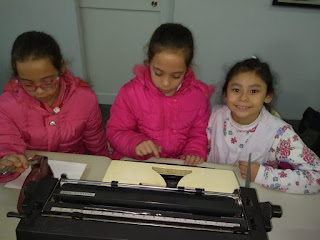 se observan unas alumnas escribiendo en una vieja máquina de escribir