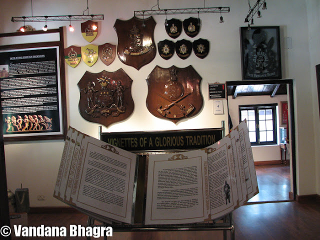 The Army Heritage Museum: An eye opener to Shimla’s history  : Posted by Vandana Bhagra on www.travellingcamera.com : Hidden amidst huge pine trees, as you circle down from Kennedy House passing through Kumar House towards the Annadale Ground the sight of this huge open grass turf is something to be awed.  As you step inside the Ground, a guard posted there will politely guide you towards the Army Heritage Museum which is opened from April to October from 10am-2pm, 3pm-5pm and during winter from November to March from 10am-2pm, 3pm-4pm. The road leading towards the museum is decorative with 25 pounder artillery gun at the entrance, 40mm antiaircraft gun, 100 mm artillery field gun, manicured lawns and landscaped gardens. Inaugurated by former chief minister Virbhadra Singh on September 20, 2006 this museum has been dedicated to the citizens of Shimla by Lt Gen KS Jamwal, but quite sad that very few citizens actually know about this amazing museum.The history of Annadale is associated with the British rule asfrom being a nondescript village, under the Viceroy, John Lawrence, Shimla was officially declared as the Summer Capital in 1864 of the British Empire, a status retained up to India’s Independence. Annadale since its inception in the 1930s has been a favourite place for picnic parties, fetes and fancy fairs, birthday balls, flower and dog shows, races, gymkhanas, polo and other tournaments hosted by the army. The race course dates back to 1840 and Sir Mortimer Durand inaugurated the first football tournament in 1888, which was later moved to Kolkata. Regular military activities have ensured upkeep of this place as its pristine glory amidst the sylvan surroundings is still immaculate. As you walk towards the main building huge stone planks with details of state heroes and their alma mater since 1947 can be seen. A historic note on Himachalis and their ancient linage dating back to the Aryans, who are renowned for their military valour, chivalry, traditions and politeness and were primarily recruited into the ogra Regiment of the Indian Army stands tall. As one of the planks reads, “This Museum is about the Indian Army and its soldiers, their virtues, loyalty to comrades, fidelity to an oath, courage under stress, about their mind set and military thinking, passed down from generations for over 5000 years; about regiments and the intense regimental pride which they so passionately treasure, about Indian Captain of war and their contribution which make an Indian proud”.As you step inside the main building you feel dwarfed by the humongous wall hung boards depicting the army as well as Indian history. Be it the army ethos, ancient military psychology, ancient military thinking, Mahabharta, Ramayana or the Chandragupta period, history of armies of medieval India or the first was of Independence it is all out there to be read and wowed at. It is just not a history lesson read out of books, it is like reliving it all over again. The experience is so thrilling that once you begin to read it you feel quite educated as wll as entertained. On entering the room as you walk to the left you can see a huge stone soldier dressed as a warrior and the types of helmets they wore. The wall right next to it is adorned with awards and accolades won over a period of time. Another left turn towards the next room you can see mannequins in uniforms worn during the British rule, a note on evolution of these uniforms, shoulder titles and cap badges of armoured corps. The following room towards the right takes you to the musical instruments played by the army band displayed immaculately. Walking straight ahead you can read about all the conservation efforts undertaken by the army and how Major General Thomas Hardwicke set the trend for collecting specimens of birds, mammals, insects, reptiles, nests and in due course more than a dozen were named after him. He finally bequeathed his entire collection and paintings to the British Museum, London which became the first ever comprehensive display of Indian Natural History in the world in 1820. Theinstinctive reverence and love for weapons will take you the next room where arms and ammunitions are kept. Each assault rifle or shotgun is clearly labeled for military and young enthusiasts who wish to enrich their knowledge about what was used during the pre-and post Independence era, though what’s missing are the exact dates. The wall is beautified with different kinds of axes used in action. The anti tank grenade launchers, pistols, rocket launchers, gun machine are all neatly stacked on the table with details about their city of origin. Next to this table an array of bows can be seen hanging from the wall which was used by the infantrymen made as per the length of a man. The shields, swords and knives dating during 1900’s can all be seen hung on the wall in all their shine and gleam. The armour embellished with priceless gems, gold and silver was significantly made as stress was laid on the fact that it was an essential element of war. The six horses driven carriage along with the cannon gun is a pece f art beautifully carved. Walking out into the main room after taking a full circle you are enlightened with a chronology of military events dating 2000 BC up to October 2002. Chiefs of Indian Army during the pre-Independence era starting January 1748 with Major Stringer Lawrence to General Sir Rob Lockhart  till November 30, 1945 are listed on a huge board along with the names of chiefs post-Independence dating August 15, 1947, General Sir Rob Lockhart till date as General VK Singh who took over in April 1, 2010. In a glass cupboard on one end, you can see the Field Marshal’s Baton and various kinds of ‘khukuri’s’ (Nepalese knives) and a miniature statue of Maharana Pratap on his horse.  Once out of the main hall there is another room full of army combat badges which are given to personnel, an area prohibited from photography. But just standing in the room it had an awe inspiring effect, a feeling what it means to be a soldier is suddenly instilled. The surrounding environment park is equally amazing with atleast 40 different kinds of cactuses planted in the green house, the clean manicured lawns, models of dears and bears around the park and iron-made ‘machans’ add further interest to the place.Behind the main building as you walk around the green house you can see the awesome, pristine Annadale Ground where army personnel can be seen playing golf. Turn right and you walk into the room full of honours and awards, “This section of the museum is dedicated to those valorous men and women to whom we are beholden”, as the writing on the wall states. The next room outlines the landmarks of Shimla starting from 1813 up to 2006. The walls have old photograph of Shimla and miniature models of some famous heritage buildings such as the Viceregal Lodge, now known as the Indian Institute of Advance Studies, the Gorton Castle now the AG Office, Ellerslie or the present Secretariat, the Bishop Cotton School and many more. Photographs of horse driven carriages, the Shimla Kalka toy train, old images of The Mall, Old Post Offce, Scandal Point and Lakkar Bazar will all carry you back to the 1900’s Shimla.The Conference Hall on the other end of the Museum will give you a feeling of what it’s like being in a commanding position. Displayed history of infantry regiments will equally enrich you. Moving out you can see the walls decorated with the badges of armoured corps, which traces its origin in the Indian Cavalry as some of the older regiments were formed in 1773. The twelve armoured regiments that were apportioned to the Indian Army in 1947 have grown to the present strength of 60 regiments, whose badges are now mounted on the walls. The Army Heritage Museum is a treasure house of culture and history but unfortunately the army authorities/personnel in charge are reluctant to share dates and exact reasons that have made our history so rich and important. It would have been much better if the army authorities were to engage professionals to give a guided tour of the entire Annadale complex and the museum which is being perfectly mantained by them. But despite this fact a walk around the complex is fun, entertaining and very educative.
