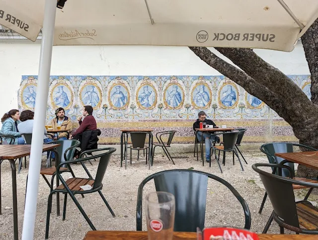 People at an outdoor cafe in Lisbon in April with a backdrop of Portuguese azulejos
