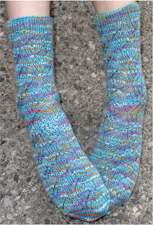 Someone wearing a pair of ribbed lace socks. The socks are blue with flecks of white, pink, and yellow.