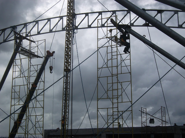 Steel erectors setting up scaffolds and jib pole with rope braces
