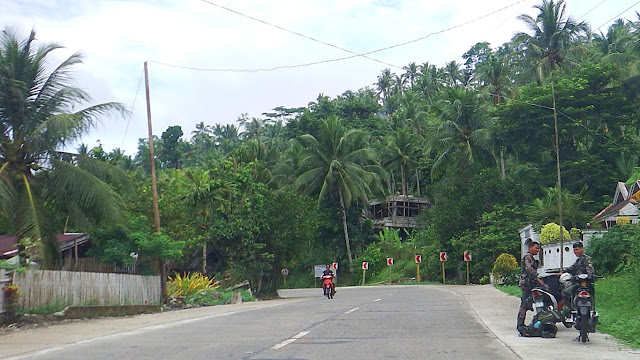 two motorcycle-riding military personnel resting on the side of the national highway in Mahaplag Leyte