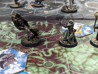 A photo of an Underworlds game in progress. A human fighter with a crossbow is in a hex next to a ghost