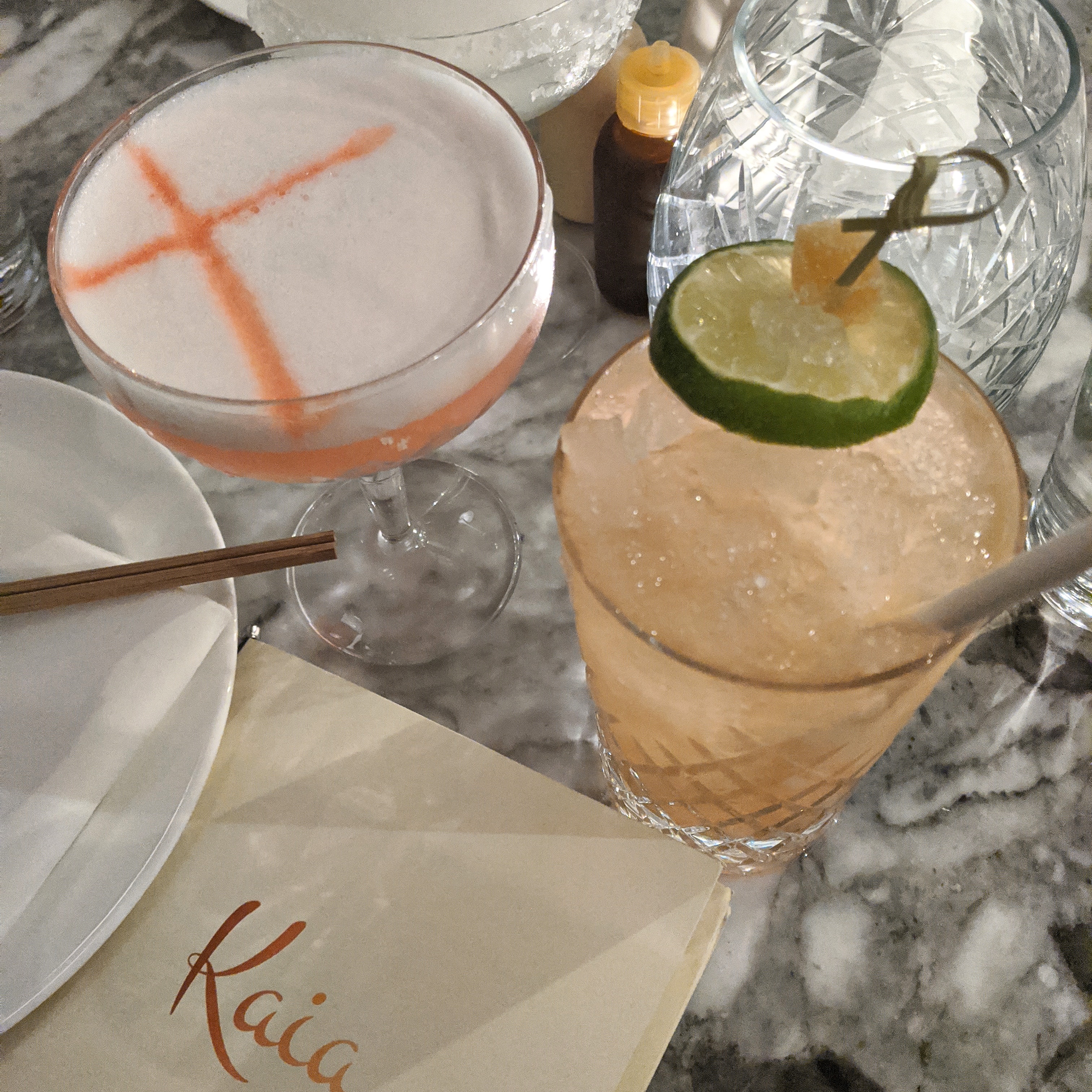 two cocktails on a marble table at Kaia, at the Ned in london