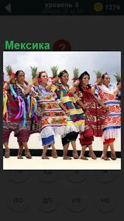 На улице Мексики стоят женщины в ряд , одетые в национальные одежды