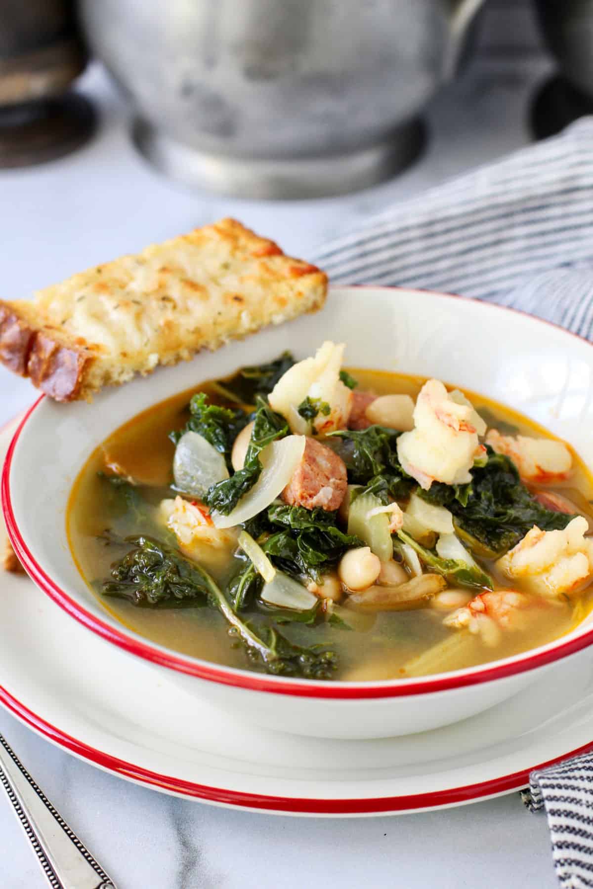 Shrimp, White Bean, and Kale Stew in a bowl with garlic cheese bread.