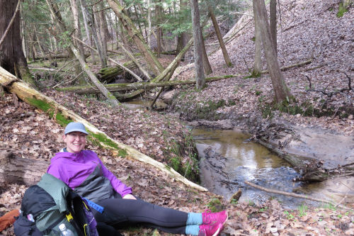 hiker sitting beside a creek