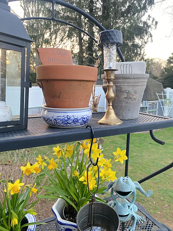 brass solar light on bakers rack with flowers