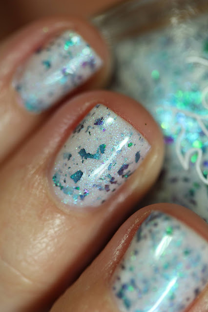 white based nail polish with green to blue to purple shifting multichrome flakes swatched on white person's nails