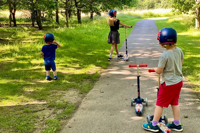 3 children scooting on a good path at Chigwell Meadow