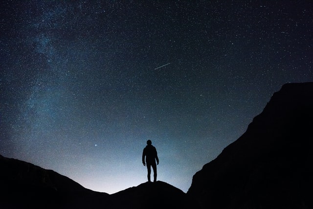 Man standing looking at stars while thinking