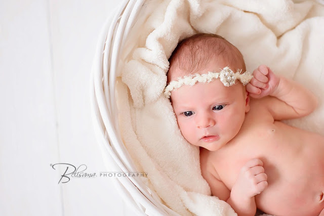 beautiful alert baby girl in white basket on white wood floor