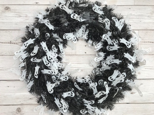A black tinsel wreath with white ghost figures on it