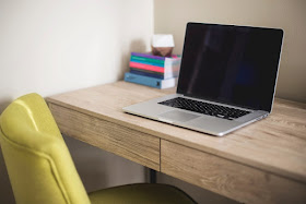 Laptop open on a tidy desk with yellow chair