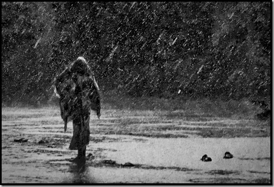 A refugee walks through an IRC Camp during an unexpected rain storm which broke up months of drought.  Kakuma Refugee Camp, Kenya.