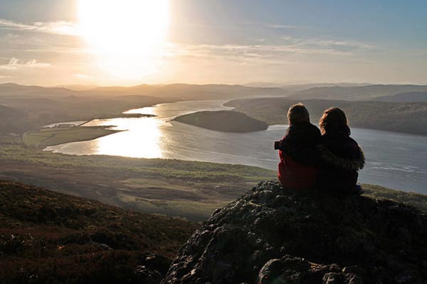 Dos hermanos observan la puesta de sol en lo alto de una montaña.