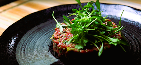 a round table that has a meat with some green vegetables on top..