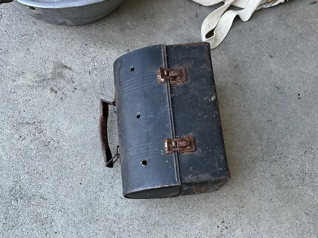 Photo of an old vintage metal lunch pail with three drilled holes.