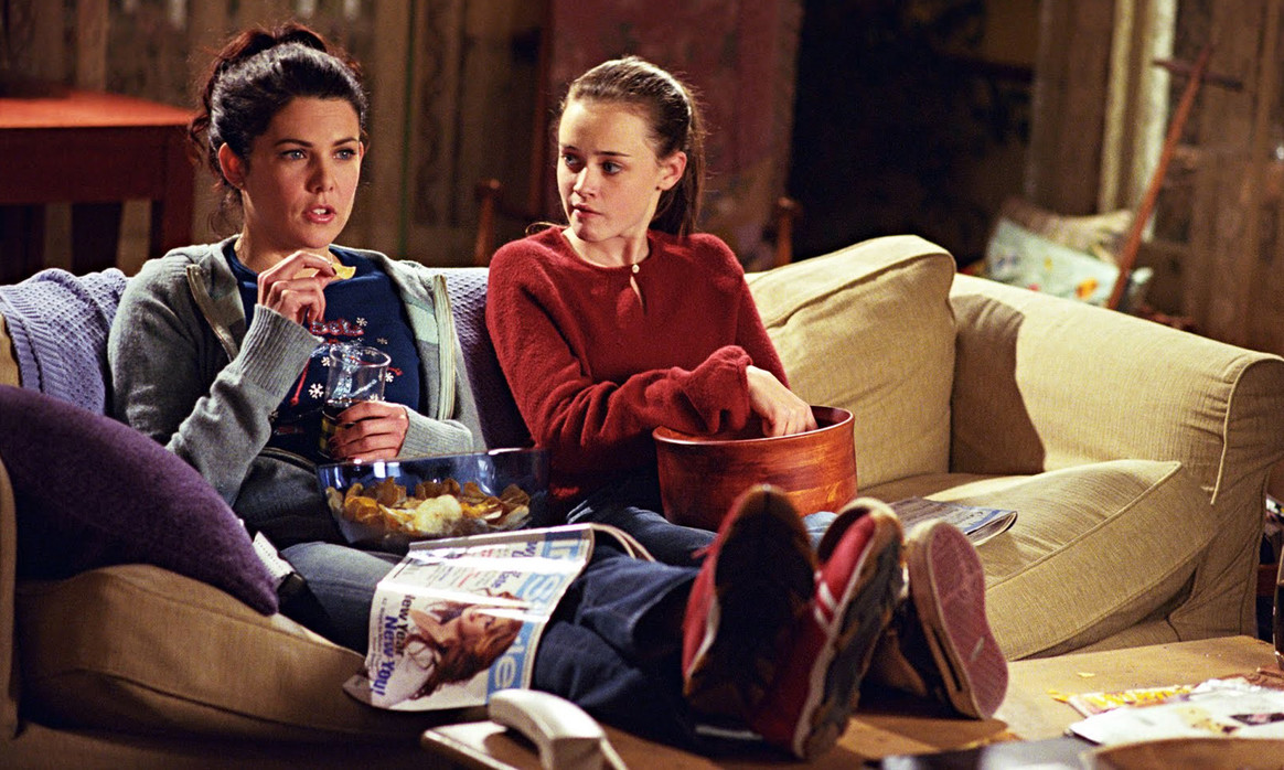 rory and lorelai sitting on the sofa eating pop corn watching a movie, gilmore girls revival, ravacholle belgium based lifestyle blog