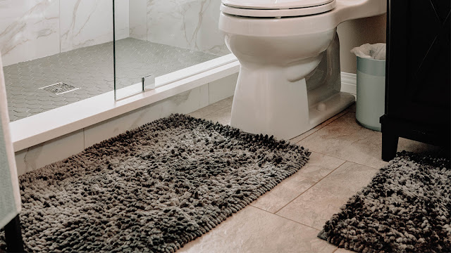 Bathroom floor with gray, fuzzy bath mats.