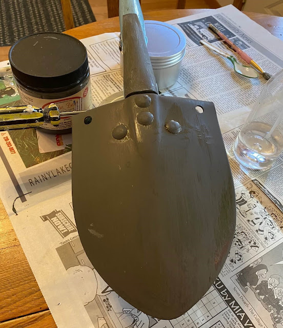 Photo of a shovel head being painted with gray chalk paint.