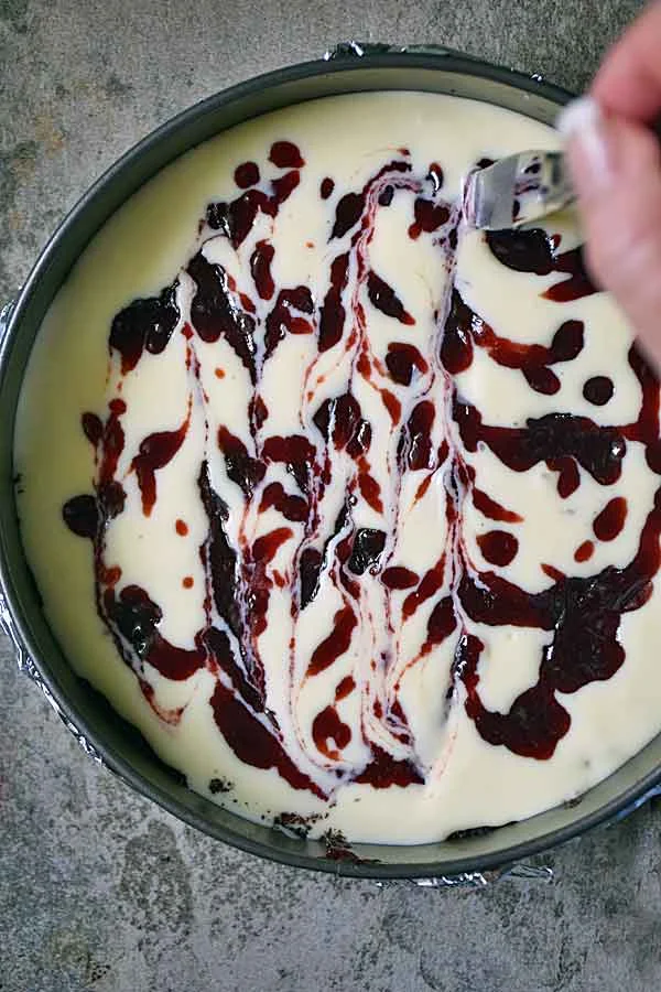 Swirling raspberry jam into the cheesecake filling to make Raspberry White Chocolate Cheesecake