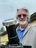 Digital camera with a fully extended zoom lens; grey haired man in the background.