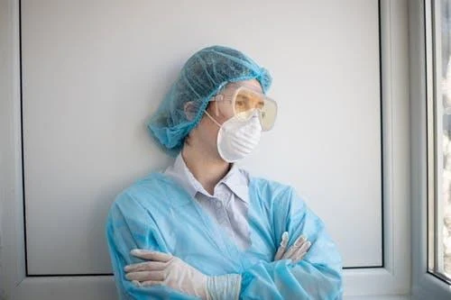 A woman in blue scrubs and a mask