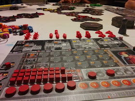 A view of the Eridani Empire play mat, with tokens on it representing being partway through a turn. The partially-constructed galactic map with player pieces on it can be seen beyond the player mat.