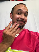 Berto, a 45 year old man wearing a pink shirt and showing off matching pink nails. He is smiling.