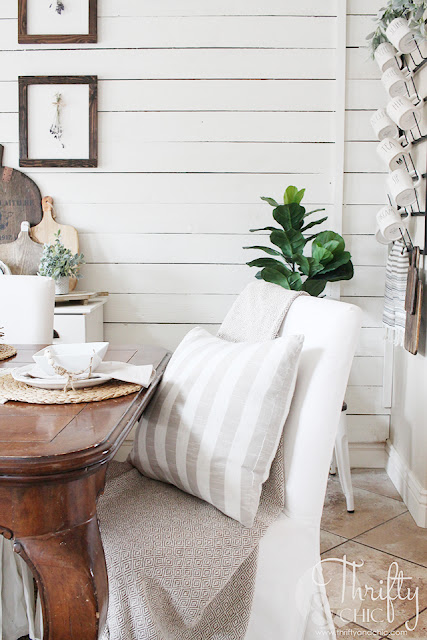 dining room with wood table, white metal chairs, white slipcover chairs, shiplap wall and wood gallery wall.