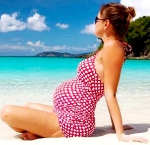 Foto de una mujer embarazada en la playa tomando sol