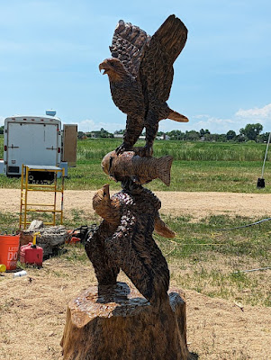 An eagle facing up and an eagle facing down, each with its talons in a fish held between them