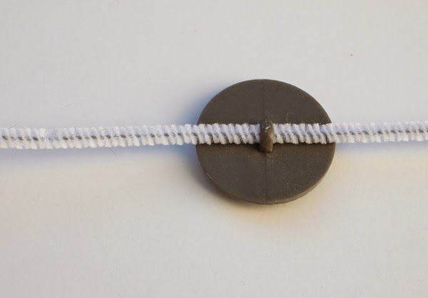 string pipe cleaner through back of button to make DIY kids jewlery