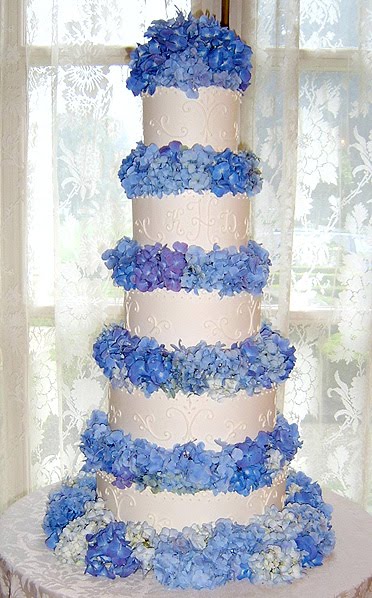 Stripy three tier white wedding cake with blue hydrangeas