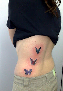 Três borboletas tatuadas na parte lateral das costas