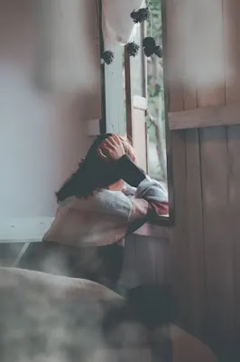 An image of a girl looking through the window- sad girl dp