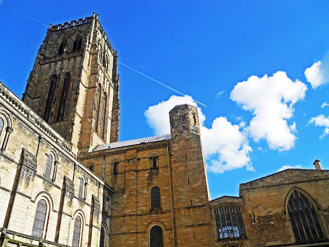 Durham Cathedral, also known as the Cathedral Church of Christ, Blessed Mary the Virgin and St Cuthbert of Durham, is located in the Durham City high above the scenic river Wear. The Cathedral is an example of the Norman Architecture and has been designated as a World Heritage Site by UNESCO. The Cathedral was founded in 1093 AD but many parts of the building are comparatively new dating back to the 15th century.  This is the Northern side of the Cathedral, which faces the Palace Green. From here the entire Northern face of the Cathedral is visible. On the West of the Cathedral,there is a deep gorge. Here you can see my friends posing for pictures. The Great Central Tower of the Cathedral, built in the 15th Century, contains detailing in Gothic styles. The atmosphere is further emphasized by the centuries old graves in the front.These are the West Towers built over a deep gorge. The archway towards the centre of the photograph is the main visitor's entrance. St. Cuthbert's Cross on the in the Front of the Northern Face of the Cathedral. The Vistor's Entrance and Great Tower. Photography is not allowed inside the Cathedral. In case you want to see what is inside, you can go through the Cathedral Website at http://www.durhamcathedral.co.uk/introduction/gallery. There are some stunning stained glass paintings embedded in magnificient arches made mostly in Gothic and Romaneque styles.  These are the cloisters where you can find a restaurant, a collection of St. Cuthbert's treasures and an audio-visual show about St. Cuthbert's Life.  The Cloisters from the inside. A picture of the Central Tower shot from the cloisters. Notice the plane in the sky, represents a contrast between the classic architecture and the contemporary..The Western Towers from one of the arches of the Cloisters. Durham Cathedral, North-East England, religious,  Christianity, Gothic, Romanesque, UNESCO, World Heritage, Churches,  Cathedral, Norman, Durham,St. Cuthbert