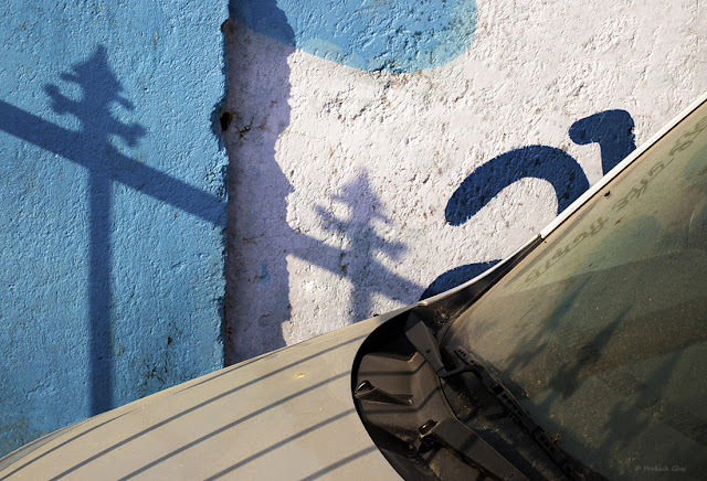 A Minimalist Photo of a part of an Abandoned Car, parked against a textured Indian Wall in Jaipur City.