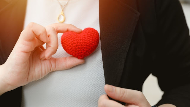 A woman is holding a red heart in her hand.