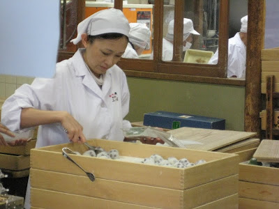 A worker grabbing fresh mochi from a tray