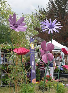 Giant purple and red model flowers with a gazebo and trees in the background