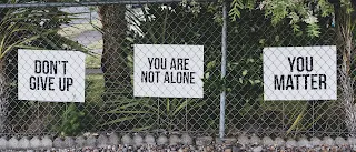 Signs saying, "Don´t give up" ,"You are not alone" and "You matter", posted on a wire fence.