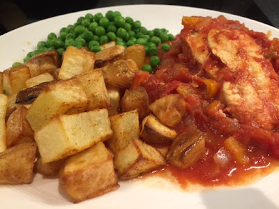 A portion of Spanish Chicken on a white plate  with peas and roast potatoes