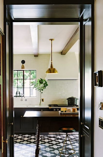 Modern kitchen with cement tiles, black cabinets, and brass pendant lights