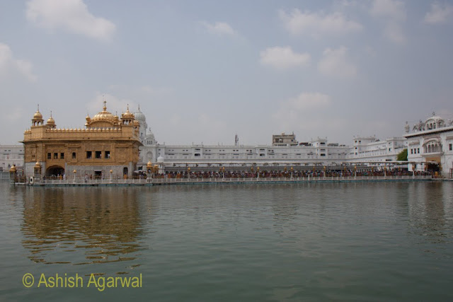 Darker image of Darbar Sahib and causeway full of tourists in the Golden Temple complex